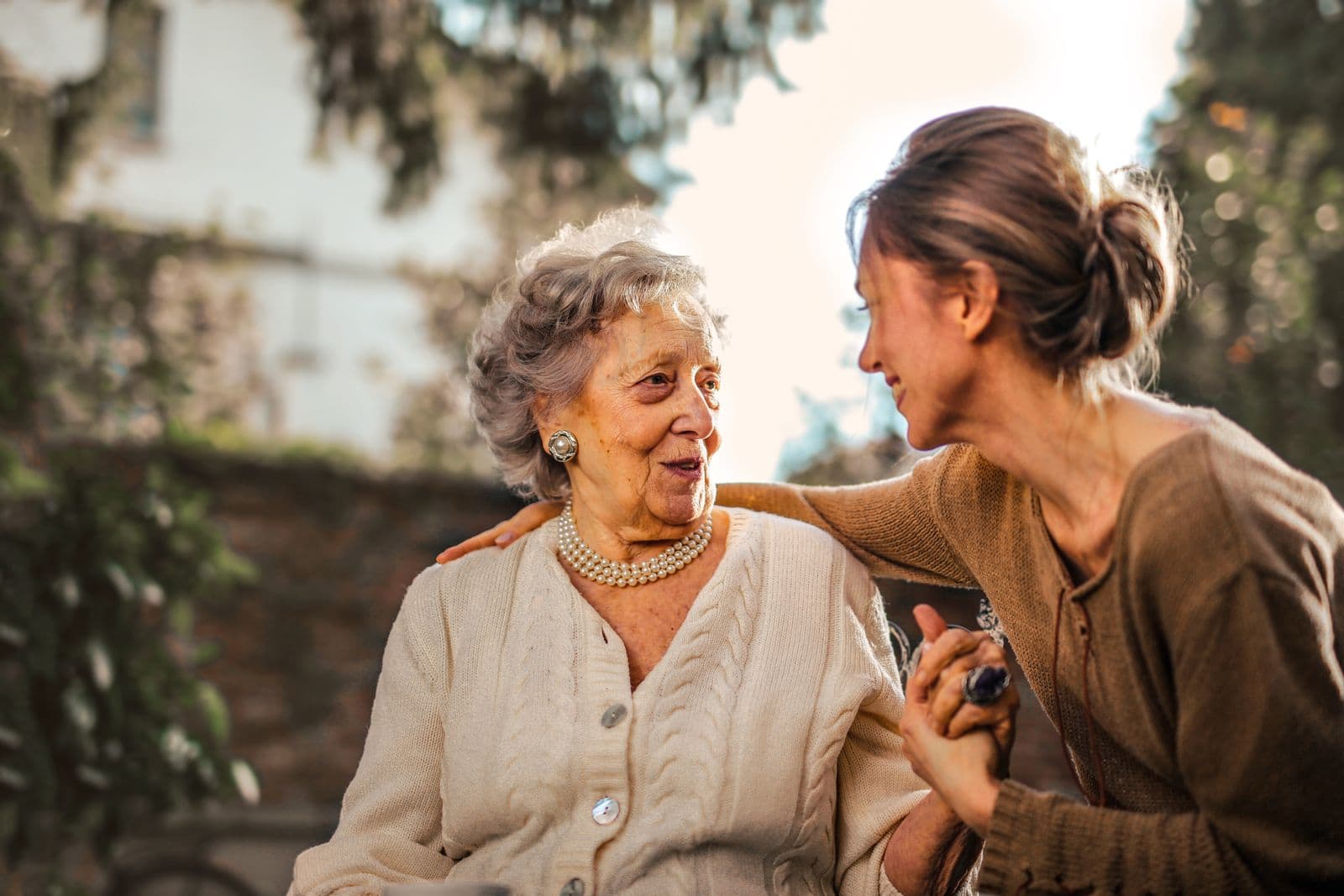 A senior woman sharing a warm moment with her adult daughter in a garden